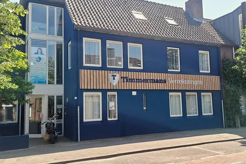 Een blauw pand met de naam op de gevel en de ingang links.